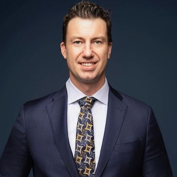 Professional man in navy suit and patterned tie.