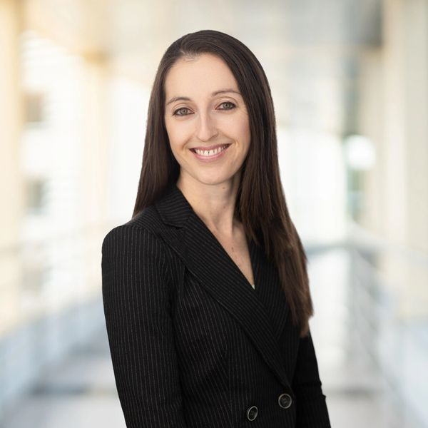 Professional woman in black blazer smiling.