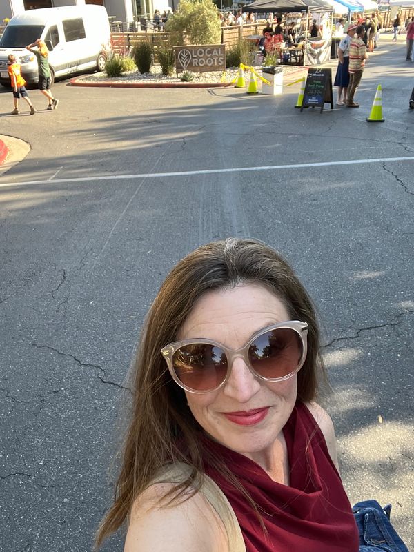 Tiffany Boyd-Hodgson selfie with Local Roots brewery and pop-up tents in background.