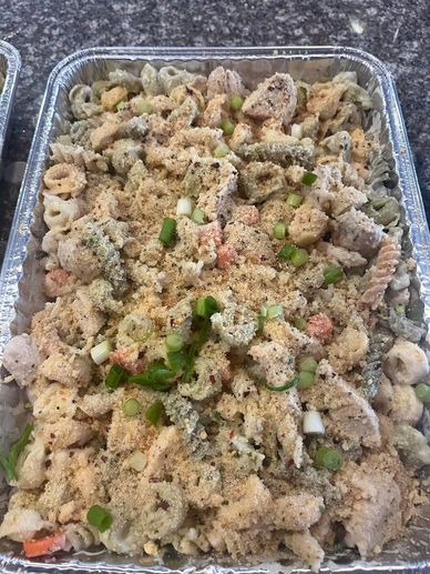 Picture of an aluminum pan filled with noodles, chicken and alfredo sauce topped with bread crumbs.