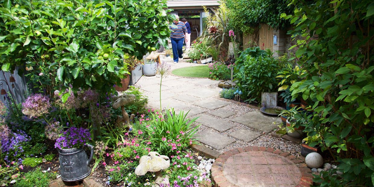 A vibrant garden path with colorful flowers and greenery leading to a garage.