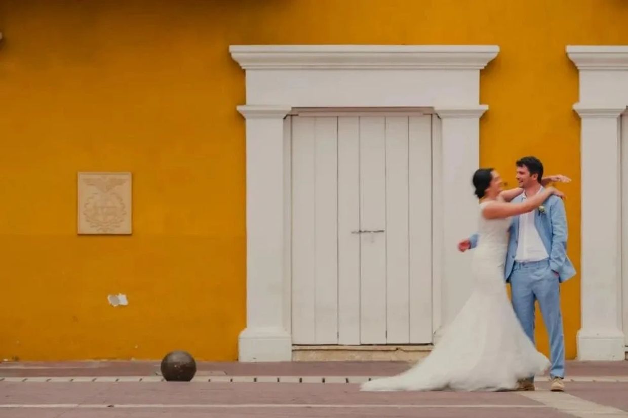 Couple celebrating their intimate elopement in front of a colonial yellow wall in Cartagena, Colombi