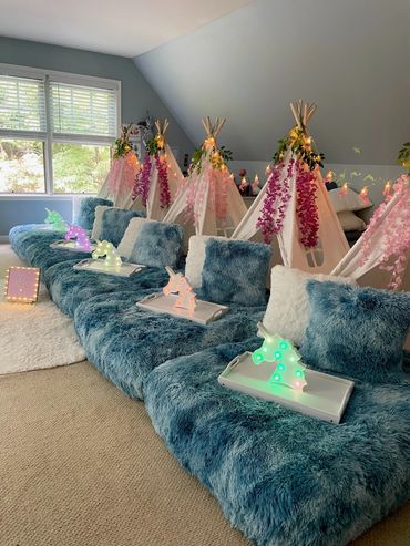 Cozy indoor teepee setup with fluffy cushions and colorful lights.