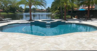 Travertine pool deck with spa by lake in Miami Lakes
