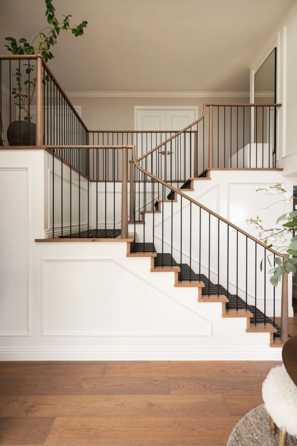 Elegant staircase with wooden steps and black railings in a modern home.