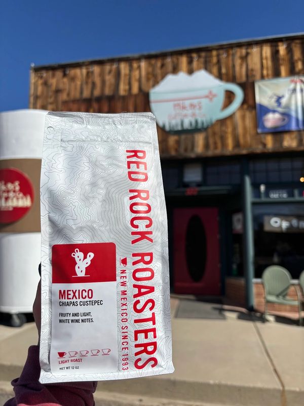A bag of Red Rock Roasters coffee held up outside a coffee shop on a sunny day.