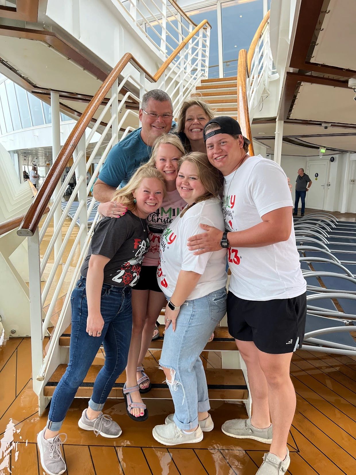 A happy family group posing on a ship staircase, wearing festive shirts.