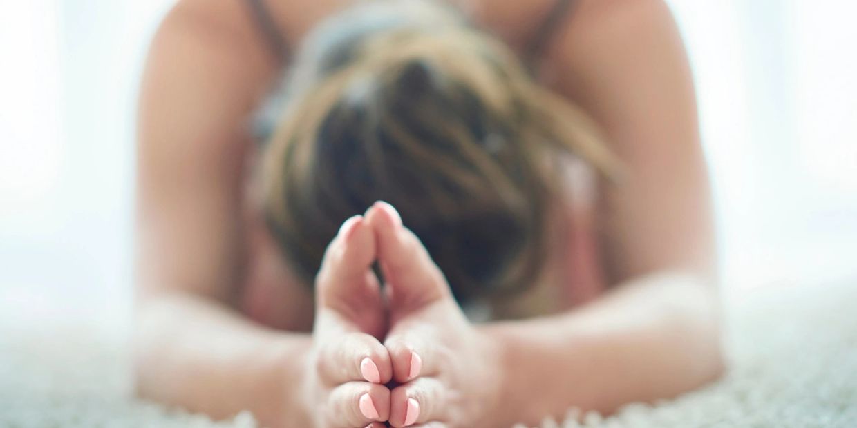 Person stretching forward, touching their feet in a yoga pose.