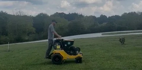 A team member of Knoxville Landscaping on a ride on aerator. 