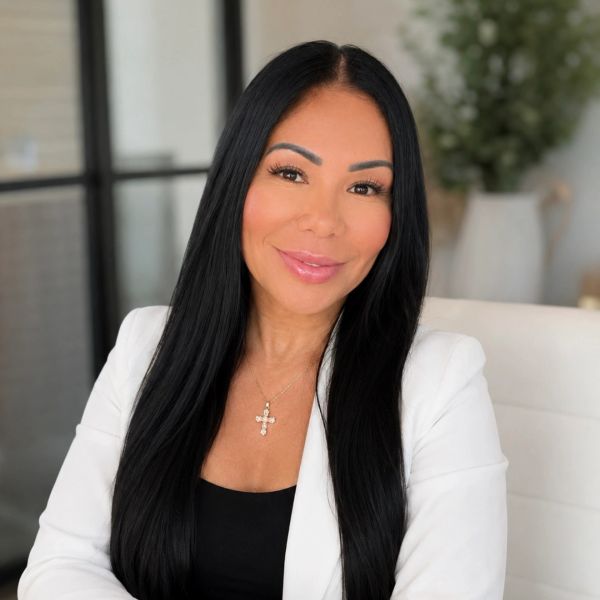 Confident woman with long black hair and white blazer.