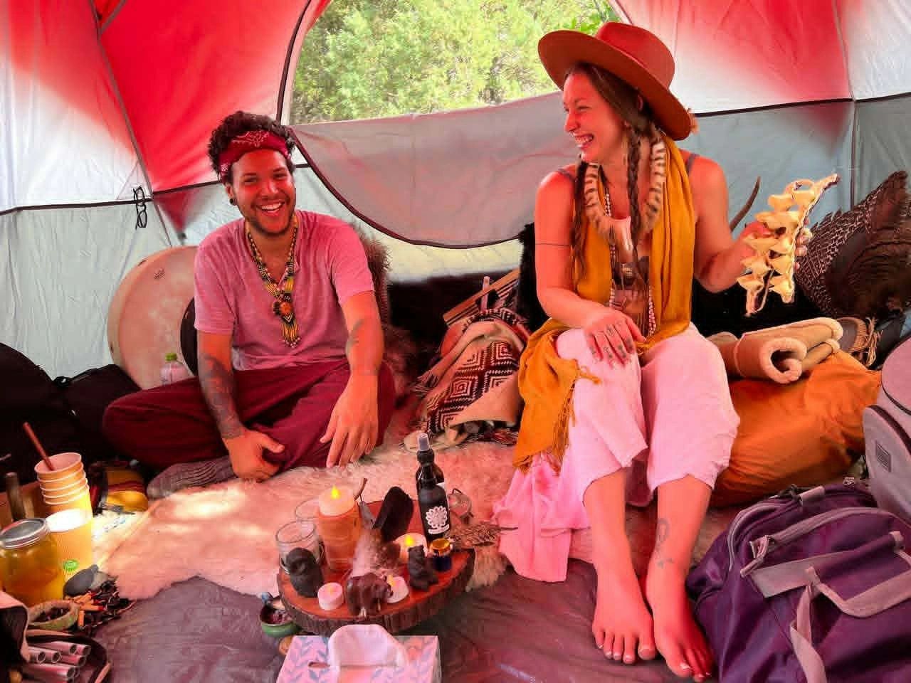Two friends smiling and enjoying inside a colorful tent.
