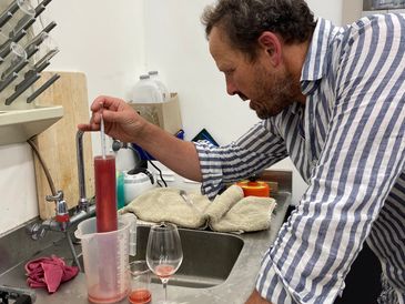 Man using a hydrometer to measure liquid density.
