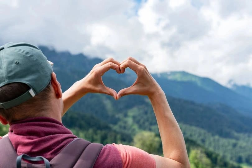 Person making a heart with hands overlooking Adirondack mountains near The Alpine Homestead in Olmst