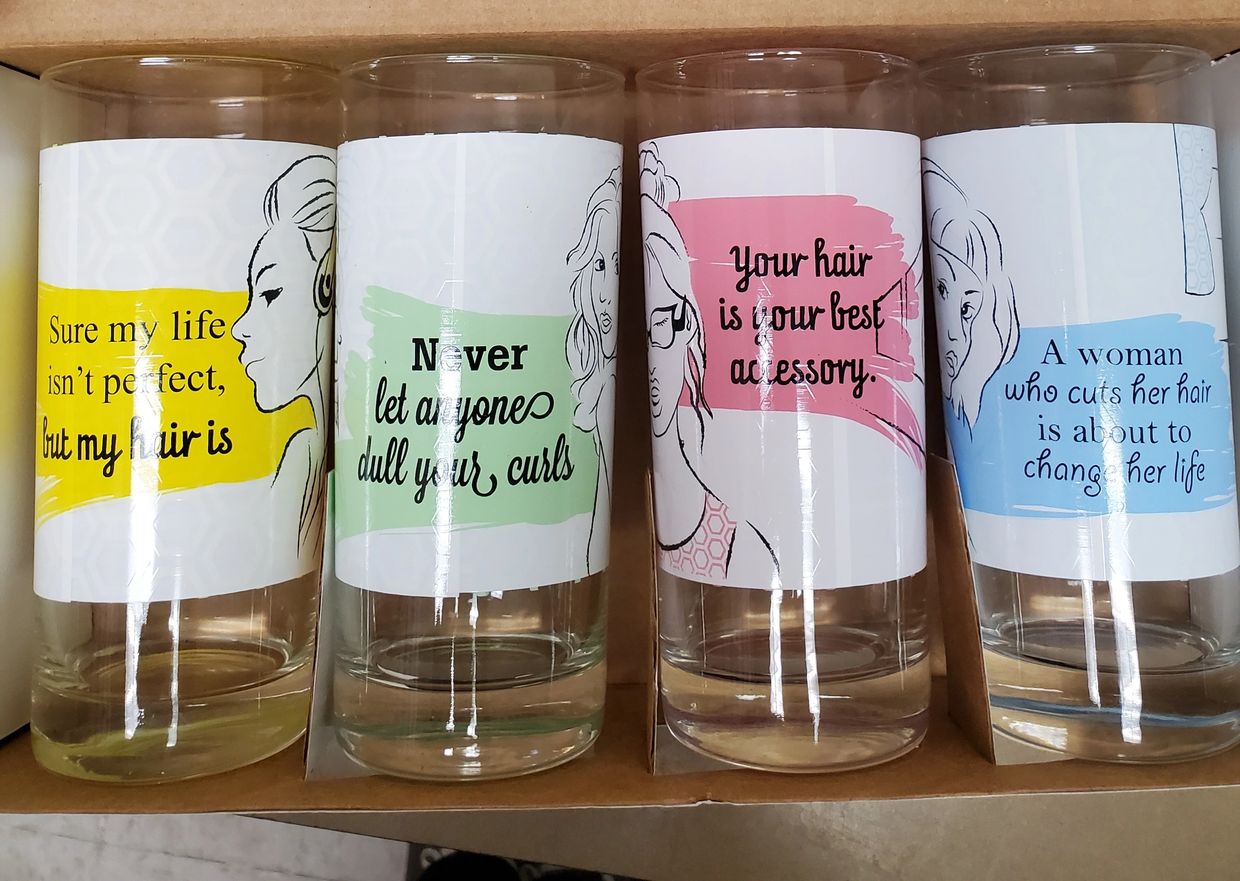 Four glasses with empowering hair-related quotes and female illustrations.
