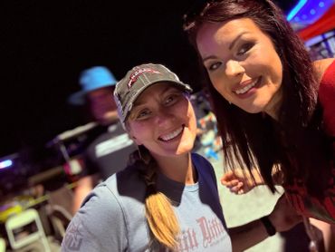 Two women smiling and posing for a selfie at night.