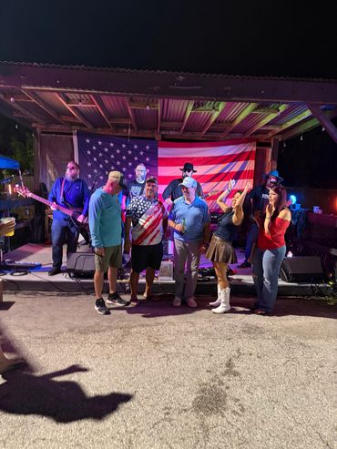 Group of people posing in front of an American flag on a stage at night.