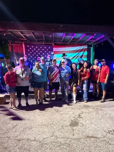Group of people posing with American flag in background.