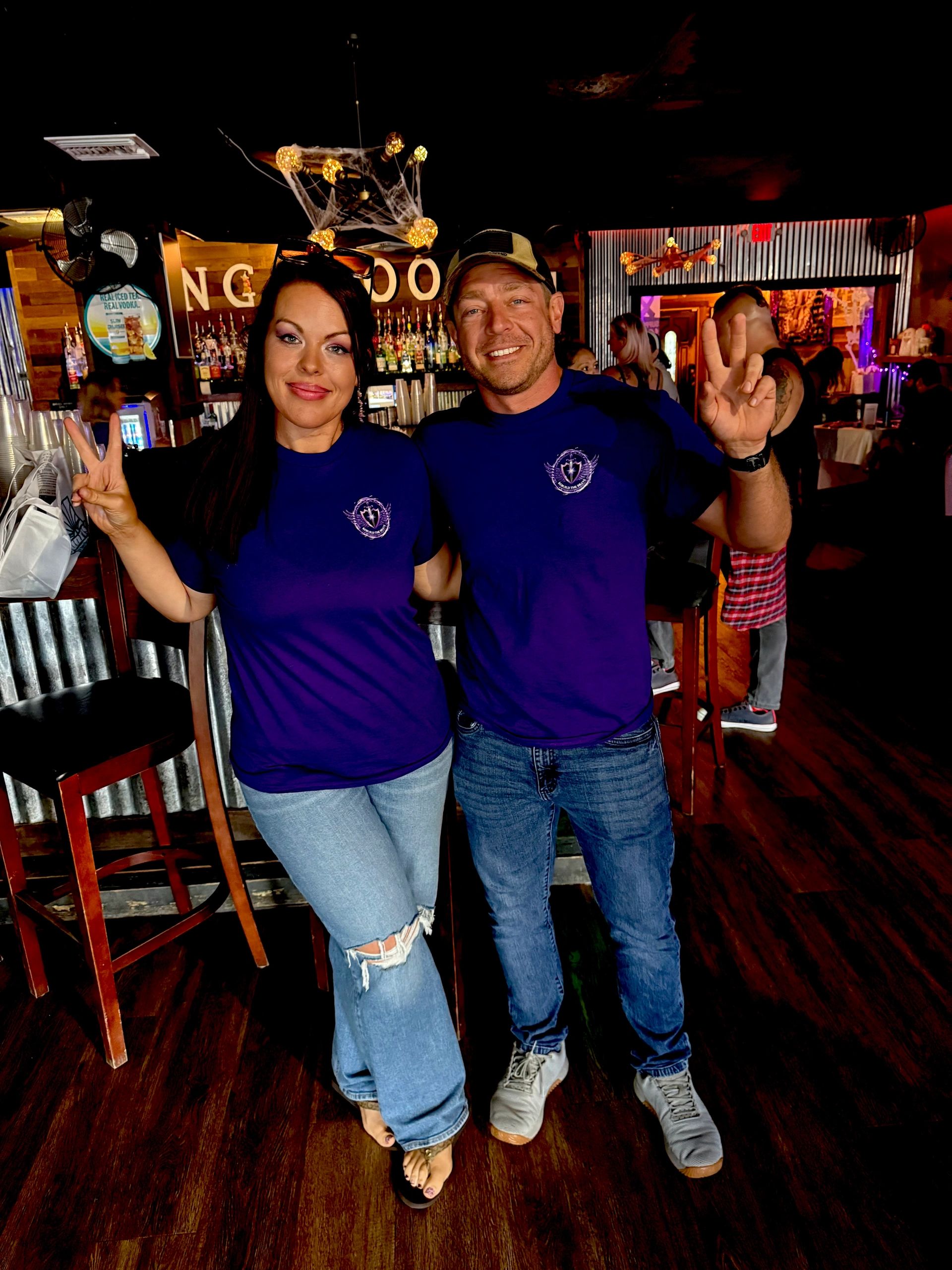 Two people posing with peace signs in a bar setting.