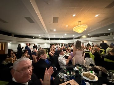 People clapping at a formal event in a banquet hall.