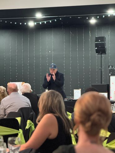 Man speaking on stage to an audience at an event.
