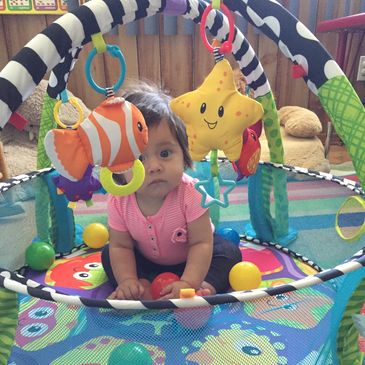 Baby playing in a colorful activity gym with toys.