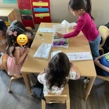 Children engaged in a classroom activity at a table.