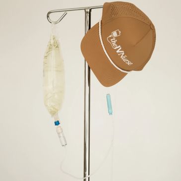 A brown nurse cap hanging on an IV stand with a saline bag.