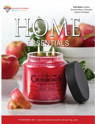 A lit Crossroads apple-scented candle with fresh apples in the background.