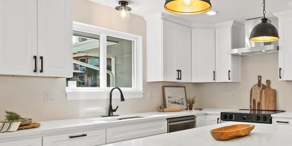 Modern white kitchen with island and black bar stools.