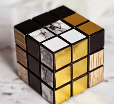 Stylish Rubik's Cube with black, white marble, gold, and wood textures.