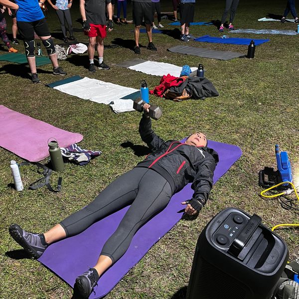 A nighttime outdoor fitness class with participants exercising on mats.