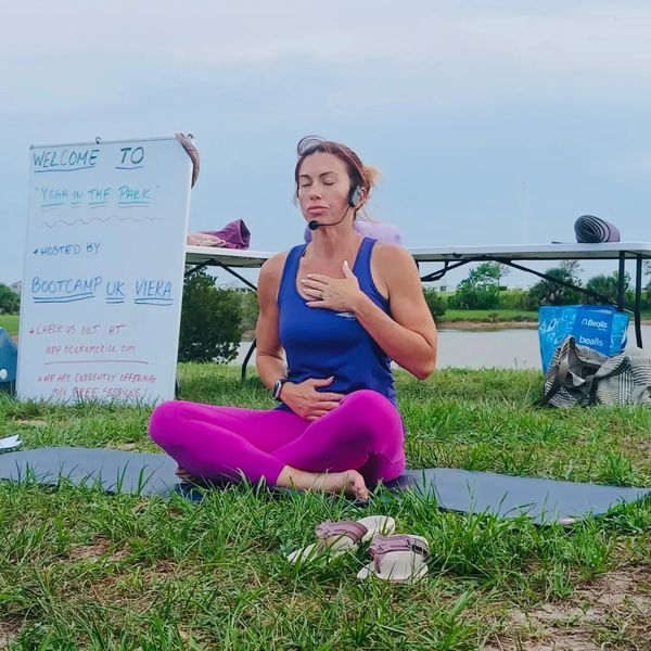 Woman meditating outdoors in a yoga session with a microphone headset.