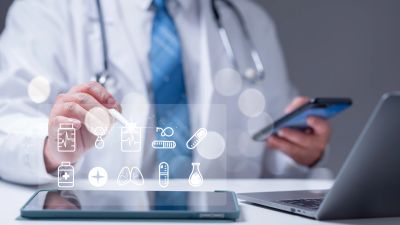 Doctor interacting with digital medical icons and using a smartphone and tablet.