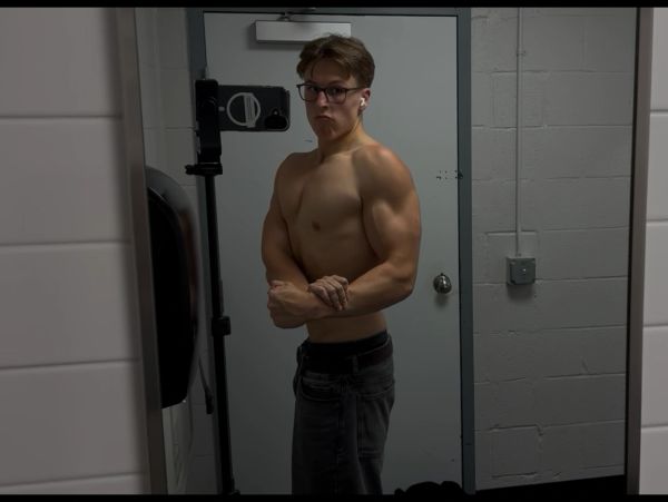 Young man flexing muscles in front of a mirror.