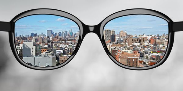 City skyline seen clearly through eyeglasses against a blurred background.