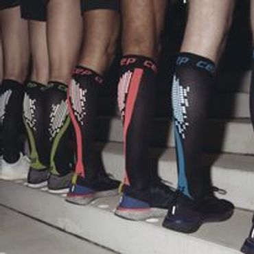 Five people wearing colorful compression calf sleeves standing on stairs.