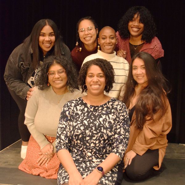 Seven diverse women smiling together in a group photo.