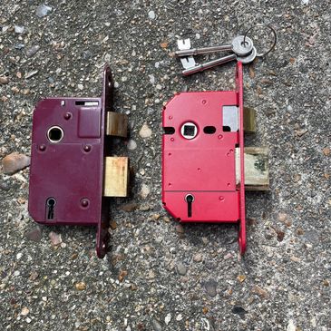 Two mortise locks and a set of keys on a rough surface.