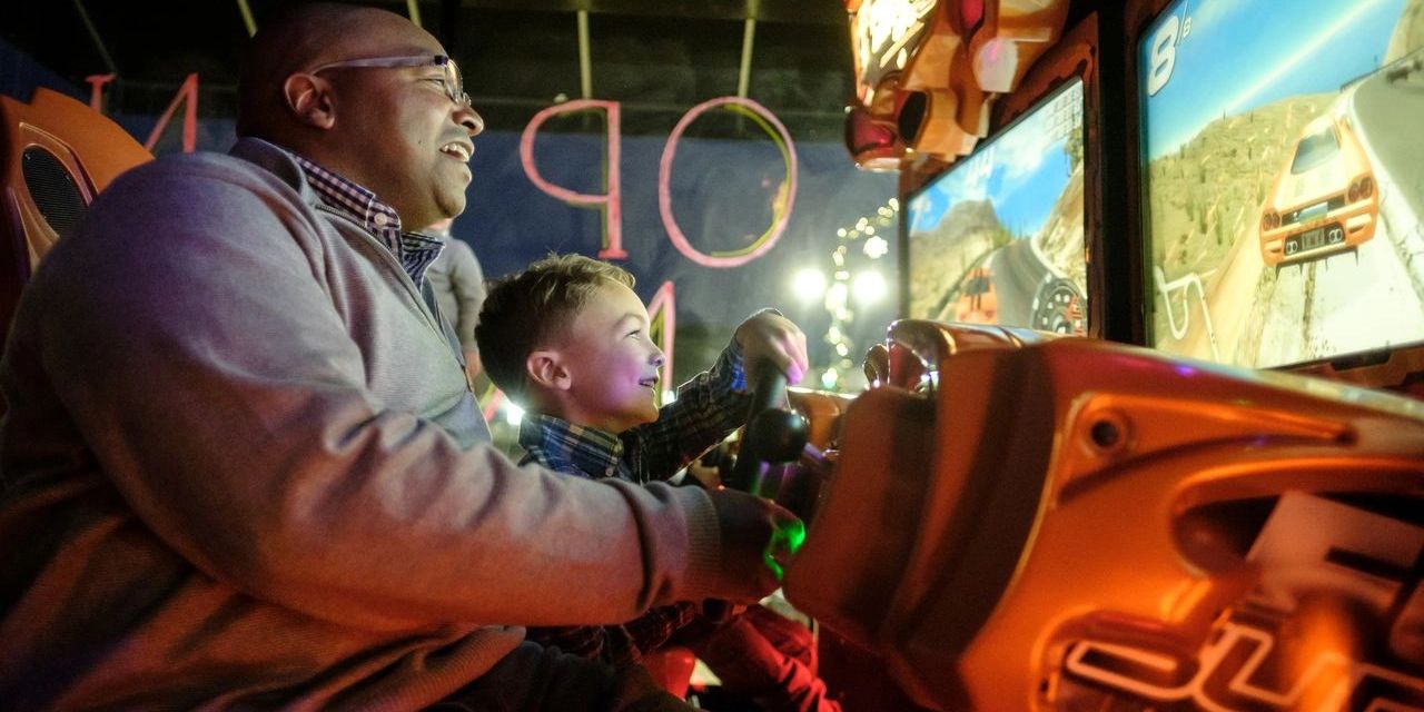 Adult and child playing a driving arcade game.