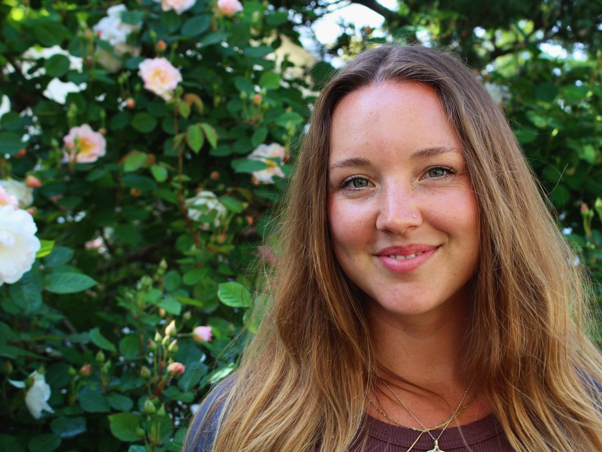 Smiling young woman with long hair in a garden.