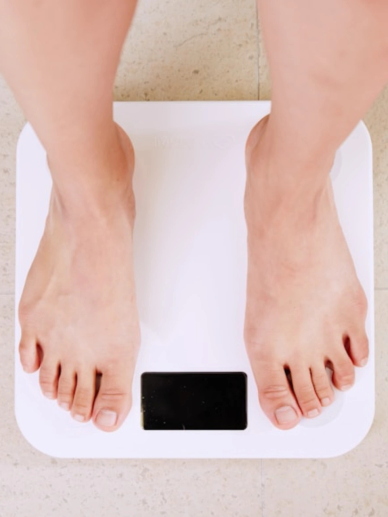 Person standing on a white digital weighing scale.