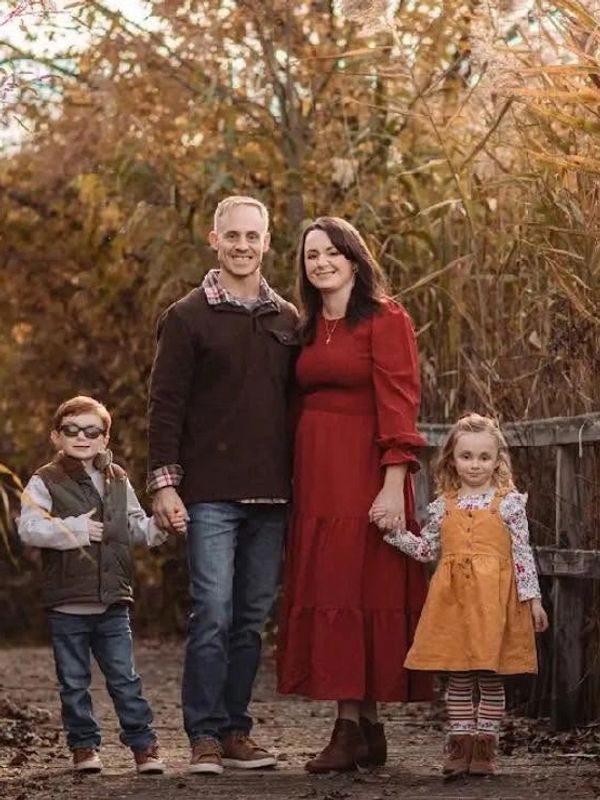 Family of four posing outdoors in autumn.