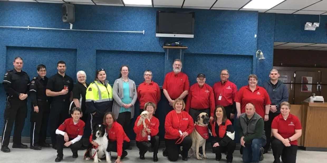 Group photo of diverse community workers and volunteers with pets indoors.