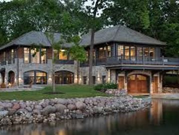 Luxurious lakeside house with stone and wood exterior at dusk.