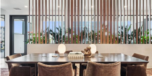 Modern dining room with wooden slat divider and cozy chairs.