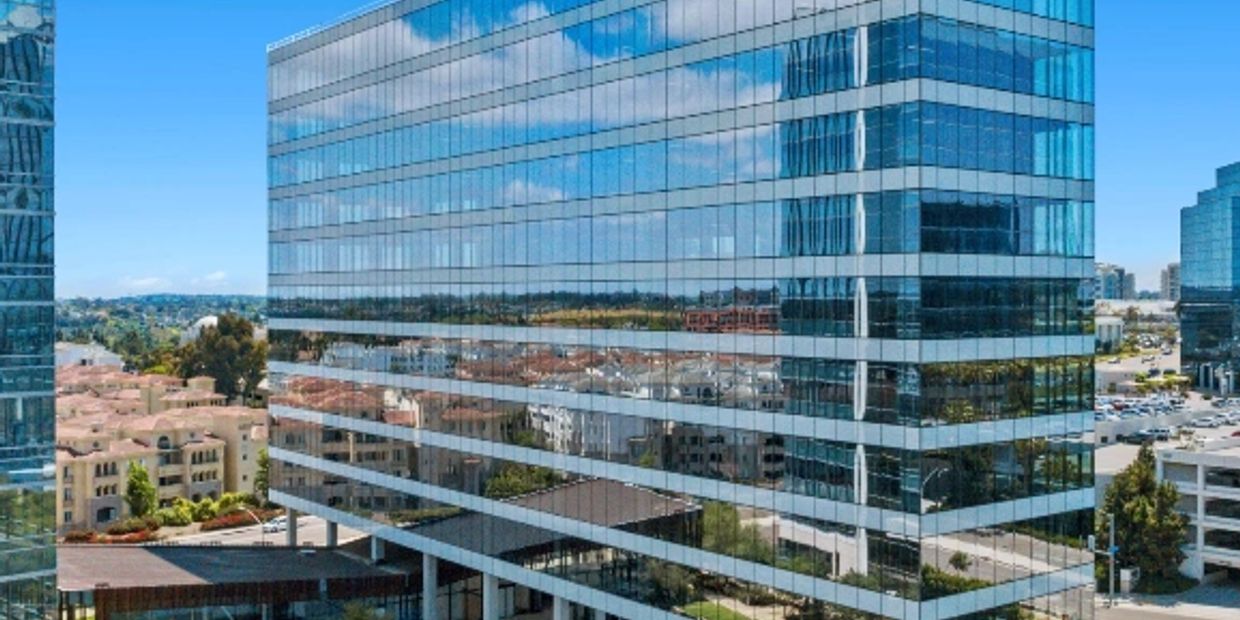 Modern glass office building reflecting the cityscape on a clear day.