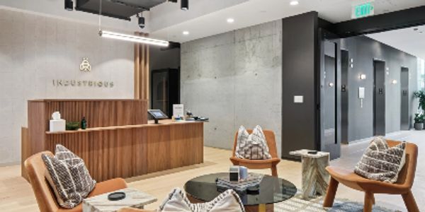 Modern office lobby with wooden reception desk and stylish seating area.