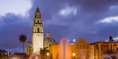 Evening view of a historic tower and fountain under a cloudy sky.