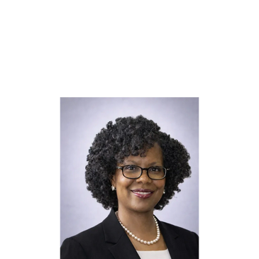Professional woman with curly hair, glasses, and pearl necklace.