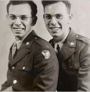 Two smiling soldiers in vintage military uniforms posing together.